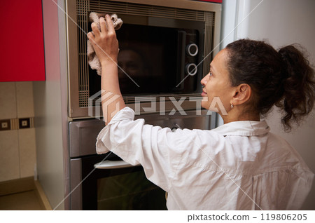 Woman cleaning kitchen microwave with a cloth 119806205