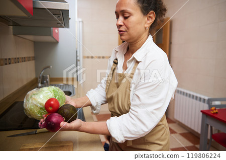 Woman prepares fresh vegetables in a modern kitchen setting Woman prepares fresh vegetables in a modern kitchen setting 119806224