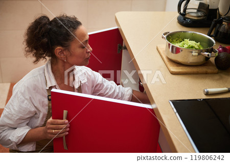 Woman organizing kitchen cabinet while preparing a healthy meal 119806242