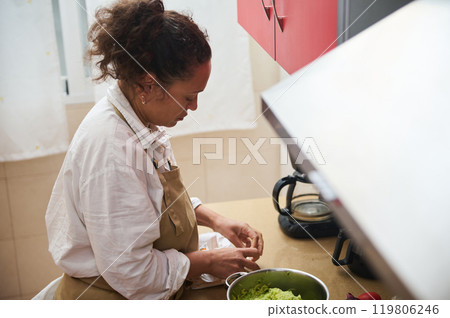 Home cook preparing a delicious meal in a cozy kitchen Home cook preparing a delicious meal in a cozy kitchen 119806246