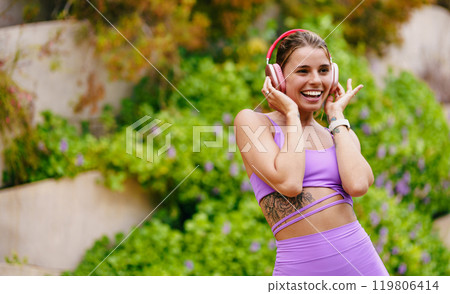 A Joyful Woman Wearing Workout Gear, Enjoying the Uplifting Music While Outdoors 119806414