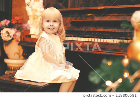 christmas smiling child little girl playing on piano at home christmas smiling child little girl playing on piano at home 119806581