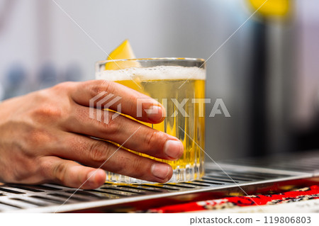 Hand holding a cocktail with lemon garnish during tasting session Hand holding a cocktail with lemon garnish during tasting session 119806803
