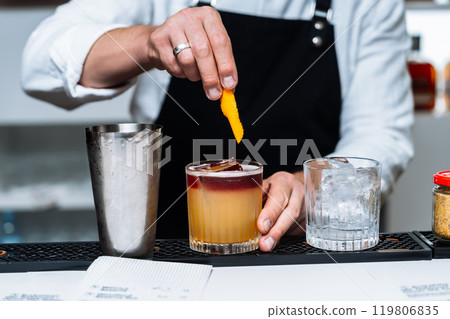 Bartender prepares cocktail with garnishing at a trendy bar Bartender prepares cocktail with garnishing at a trendy bar 119806835