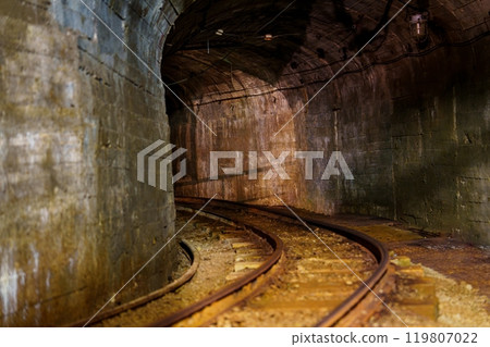 Exploring an Abandoned Old Rusty Mine Tunnel with Tracks and Mysterious Shadows in the Darkness Exploring an Abandoned Old Rusty Mine Tunnel with Tracks and Mysterious Shadows in the Darkness 119807022