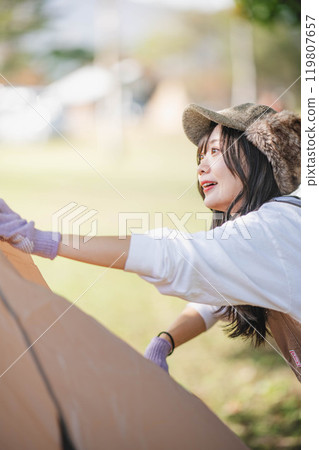 Woman setting up a tent Woman setting up a tent 119807657