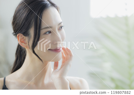 A woman in a black camisole dress standing by the window A woman in a black camisole dress standing by the window 119807882