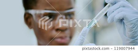 Close-up of scientist conducting scientific experiment with pipette, wearing safety goggles, focus on gloved hand and pipette in laboratory setting Close-up of scientist conducting scientific experiment with pipette, wearing safety goggles, focus on gloved hand and pipette in laboratory setting 119807944
