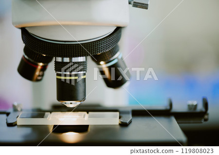 Close-up image of microscope viewing microorganisms on glass slide. Emphasizing detailed view of scientific instrument in laboratory setting 119808023