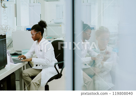 Scientist sitting in laboratory setting, engaged in research and using advanced equipment. Displaying focus and dedication, surrounded by high-tech machinery and laboratory tools 119808040