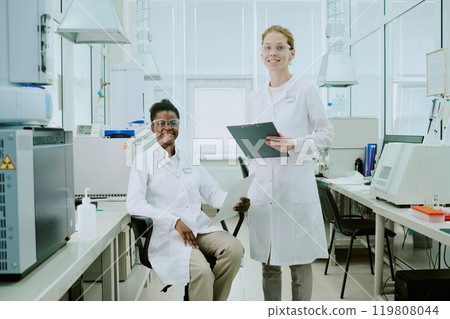 Scientists conducting groundbreaking research in high-tech laboratory, wearing lab coats and safety glasses while analyzing data and samples with advanced equipment Scientists conducting groundbreaking research in high-tech laboratory, wearing lab coats and safety glasses while analyzing data and samples with advanced equipment 119808044