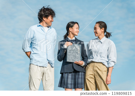 微笑的女兒和父母/家人在藍天下拿著文憑 微笑的女兒和父母/家人在藍天下拿著文憑 119809815