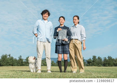 微笑的女兒和父母/家人在藍天下拿著文憑 119809817