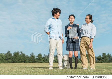 Smiling daughter and parents holding a diploma under the blue sky, family Smiling daughter and parents holding a diploma under the blue sky, family 119809818