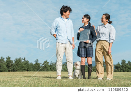 Smiling daughter and parents holding a diploma under the blue sky, family 119809820