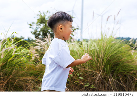 young boy is running through a field of tall grass 119810472