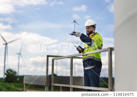 man in a yellow and black safety vest is standing man in a yellow and black safety vest is standing 119810475