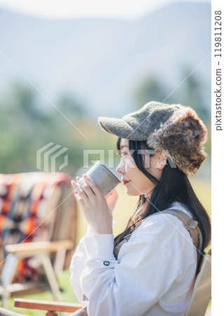 Woman relaxing at camp and having a drink Woman relaxing at camp and having a drink 119811208