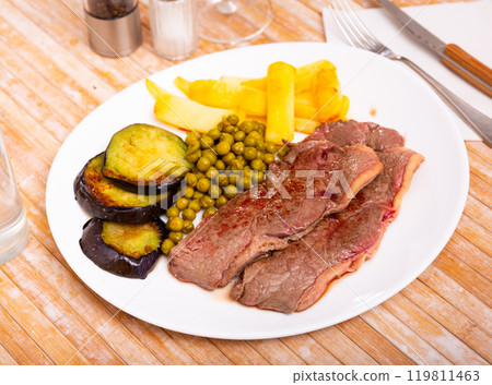 Veal tenderloin with fried potatoes, baked eggplant and peas 119811463