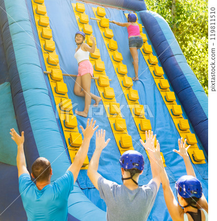 Happy young woman climbing on inflatable castle with wooden sticks Happy young woman climbing on inflatable castle with wooden sticks 119811510