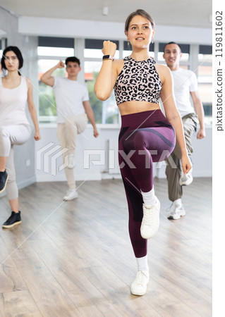 Young sports girl rehearsing modern dances during group training in dance studio 119811602