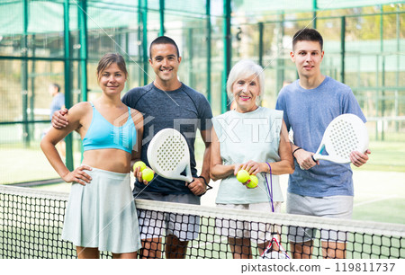 Cheerful paddle tennis players standing after match on open court Cheerful paddle tennis players standing after match on open court 119811737