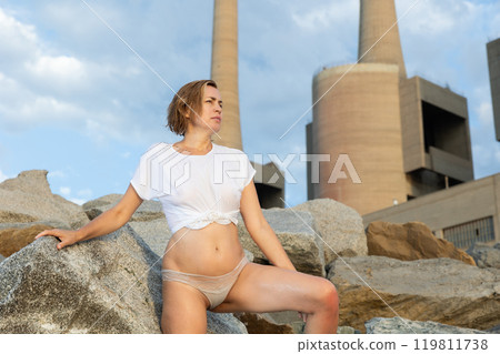 Portrait of slim woman in t-shirt and panties posing on rocky beach Portrait of slim woman in t-shirt and panties posing on rocky beach 119811738