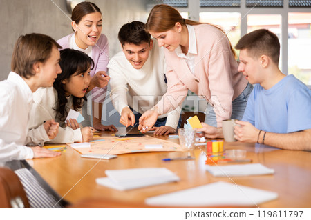 Happy students playing board game at table in campus Happy students playing board game at table in campus 119811797