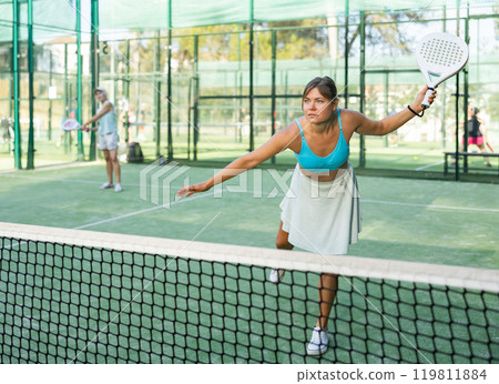 Young female paddle tennis player performing left hand forehand Young female paddle tennis player performing left hand forehand 119811884