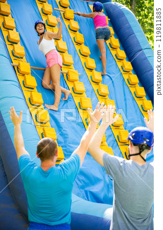 Women using sticks to reach top of slide in adventure park Women using sticks to reach top of slide in adventure park 119811885