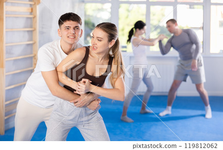 Young girl practicing self-defense techniques in pairs with guy Young girl practicing self-defense techniques in pairs with guy 119812062