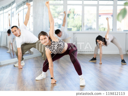 Cheerful young female dancer rehearsing popping techniques in studio Cheerful young female dancer rehearsing popping techniques in studio 119812113