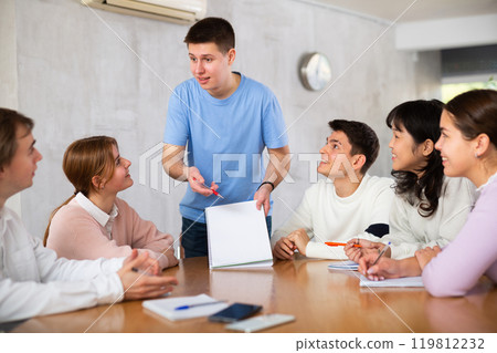 Cheerful young student discussing learning assignment with coursemates Cheerful young student discussing learning assignment with coursemates 119812232