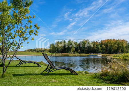 A serene and beautiful garden featuring comfortable lounge chairs next to a tranquil pond A serene and beautiful garden featuring comfortable lounge chairs next to a tranquil pond 119812500