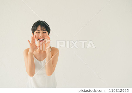 一位穿著吊帶背心的年輕女子用手摀著嘴喊著什麼 一位穿著吊帶背心的年輕女子用手摀著嘴喊著什麼 119812935