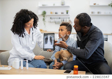 Female doctor showing x-ray on tablet to boy with concerned father 119813347