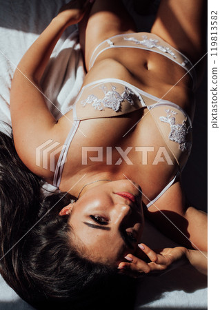 Beautiful brunette woman in lingerie in bedroom on bed in the morning Beautiful brunette woman in lingerie in bedroom on bed in the morning 119813582