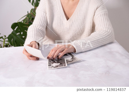 woman sitting at desk and looking at printed photos, remember nostalgia for a day of rest. photography cards, background. Mock up 119814837