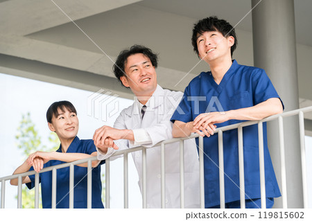 Male and female doctors, physicians, nurses, medical staff and technicians taking a break outdoors at the hospital 119815602