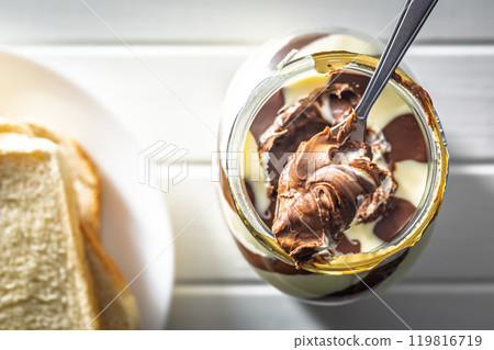 Chocolate cream spread on spoon in jar. Top view. 119816719