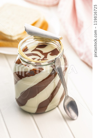 Chocolate cream spread in jar on white table. 119816725