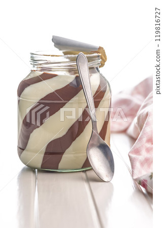 Chocolate cream spread in jar on white table. 119816727