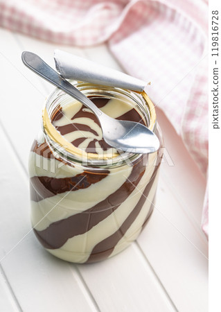 Chocolate cream spread in jar on white table. 119816728