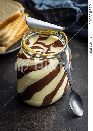 Chocolate cream spread in jar on black table. 119816730