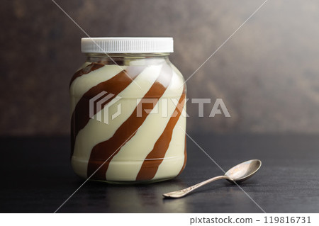 Chocolate cream spread in jar on black table. Chocolate cream spread in jar on black table. 119816731