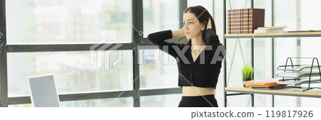 Woman in black wear adjusts hair walking across office 119817926