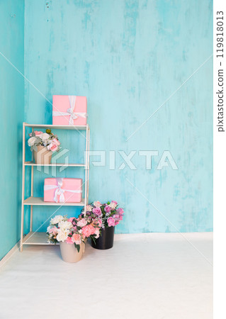 Shelf with flowers and gifts for the holiday in the interior of an empty blue room 119818013