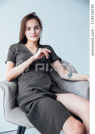 Portrait of a beautiful slender woman in a gray summer dress on an armchair 119818030