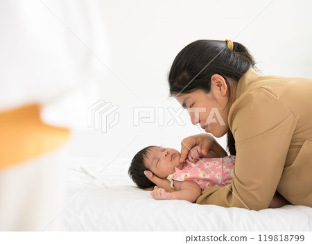 Asian mother touching newborn baby daughter chin on bed at home. Infant girl sleeping on mom arm. Love and new life concept 119818799