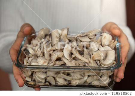 Unrecognizable woman showing into camera frozen food sliced mushrooms champignon homemade. Harvesting concept. Stocking up vegetables for winter storage 119818862